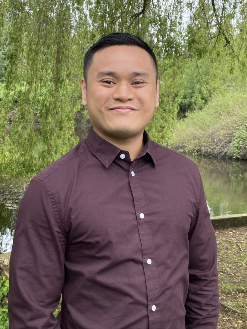 Smiling man in maroon shirt outdoors